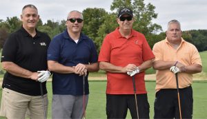 Four individuals standing at the golf tournament