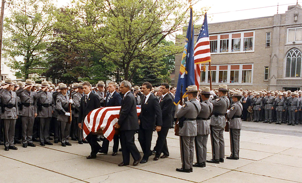 Image of a funeral with a casket covered with the american flag