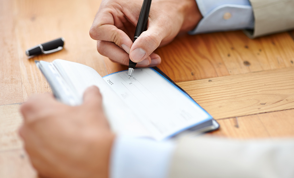 Close-up of hands signing a check